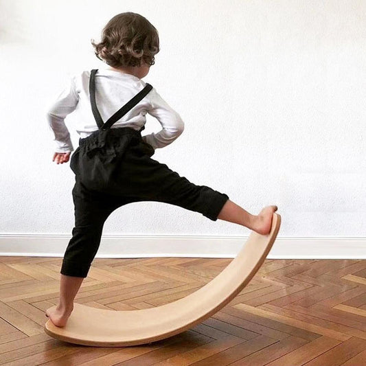 Child playing on Montessori wooden balance board toy for indoor movement and balance training.